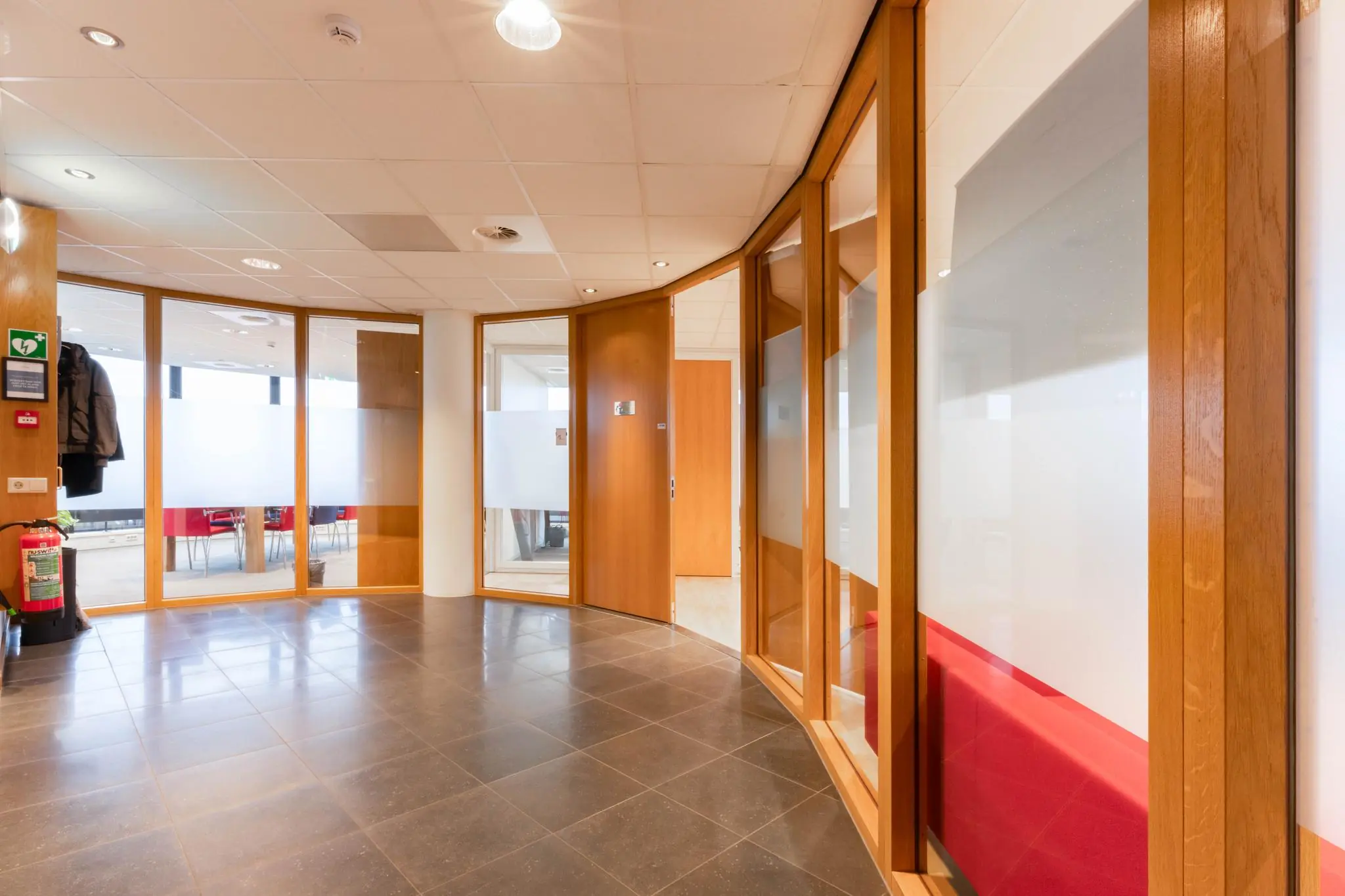 Moderne kantoorruimte aan de 1e Hogeweg met glazen wanden, houten kozijnen en een tegelvloer.